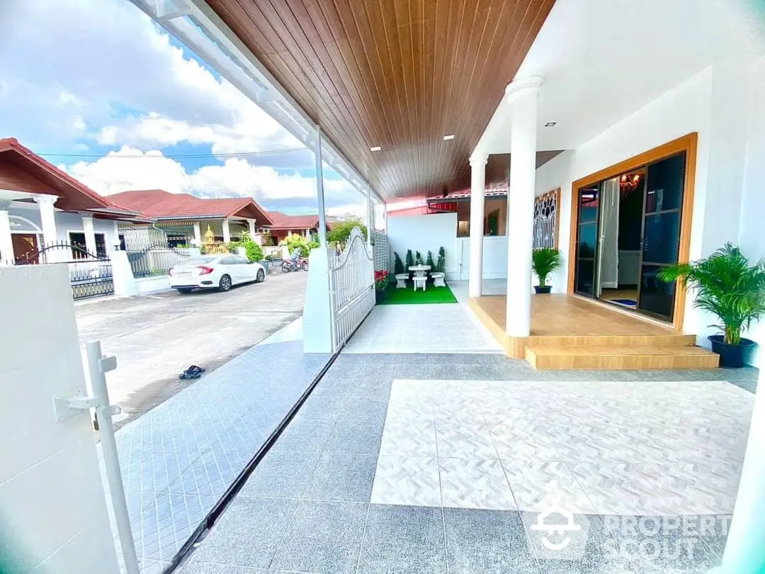 Spacious and inviting home entrance with a covered walkway, elegant wooden ceiling, and modern tiled flooring, leading to a bright and welcoming doorway.