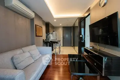 Modern living room with sleek design, featuring a comfortable sofa, flat-screen TV, and stylish kitchen area.