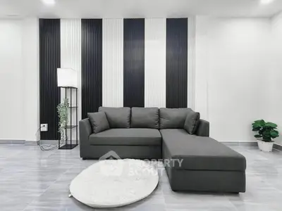 Modern living room with stylish gray sofa and chic black and white wall design.