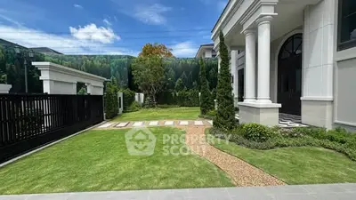 Luxurious mansion entrance with manicured garden and elegant columns