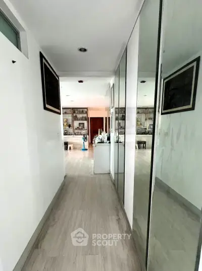 Modern hallway leading to a spacious living room with stylish decor and wooden flooring.