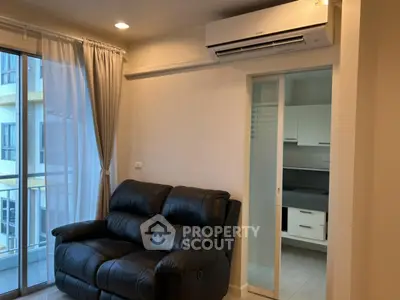 Cozy living room with leather sofa and air conditioning, adjacent to modern kitchen.