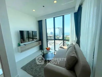 Modern living room with large windows and city view, featuring sleek furniture and natural light.