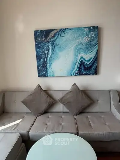 Stylish living room with modern gray sofa and abstract blue artwork