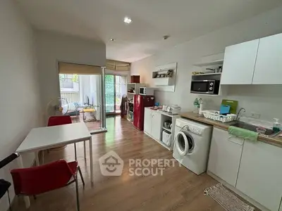 Modern open-layout kitchen with washing machine and balcony access in cozy apartment.