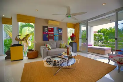 Spacious living room with modern decor and large windows opening to a lush balcony view.