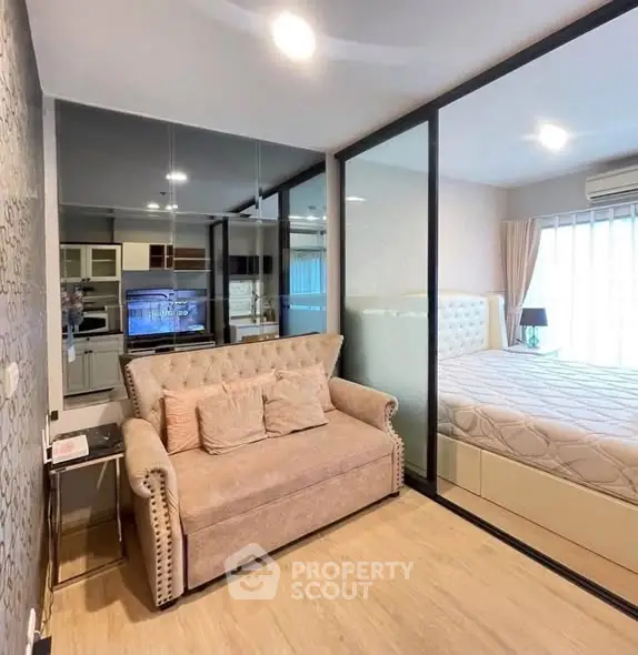 Modern apartment interior with cozy living room and stylish bedroom separated by glass partition.