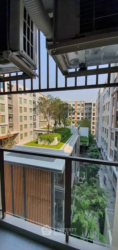 Modern apartment balcony with view of green rooftop garden and urban surroundings.