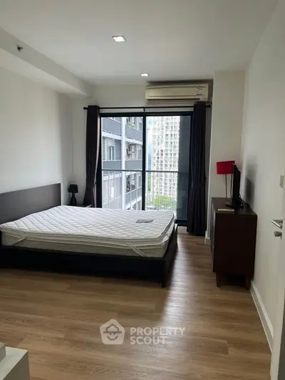 Modern bedroom with large window and city view in a high-rise apartment.