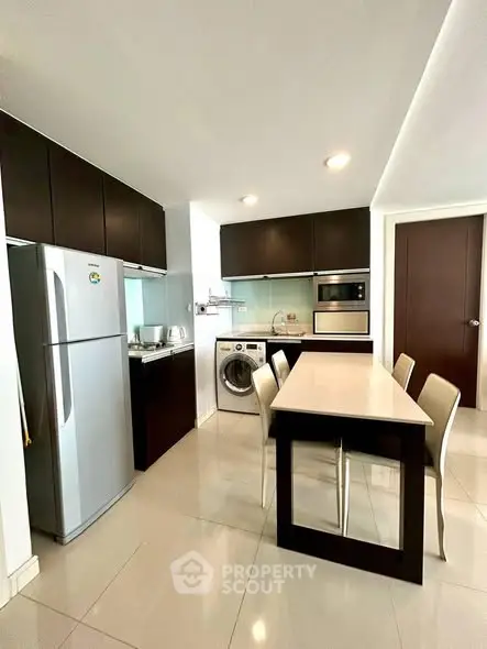 Modern kitchen with sleek cabinets, dining table, and built-in appliances in a stylish apartment.