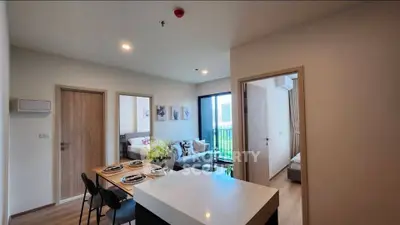 Modern open-plan living room with dining area and balcony view in a stylish apartment.