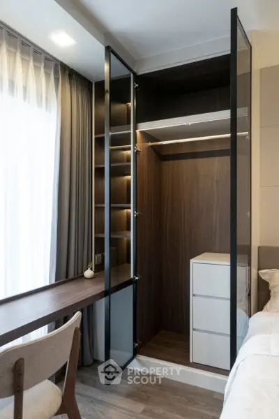 Modern bedroom with sleek glass wardrobe and cozy workspace