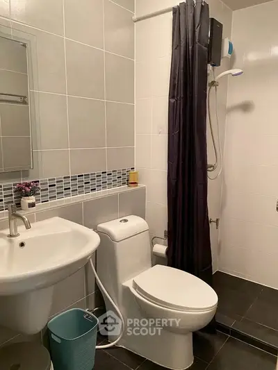 Modern bathroom with sleek fixtures and stylish tile design, featuring a shower and contemporary sink.