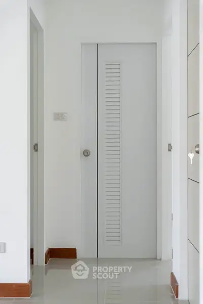 Minimalist hallway with sleek white doors and glossy tiled floor