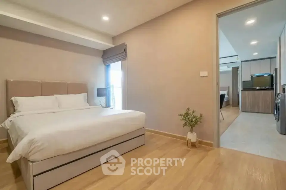 Spacious modern bedroom with elegant decor and open view to kitchen area.