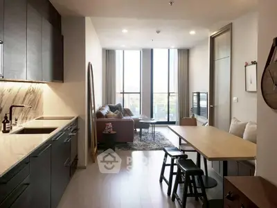 Modern open-plan kitchen and living room with stylish decor and large windows.