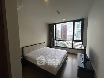 Modern bedroom with city view and large window in high-rise apartment.
