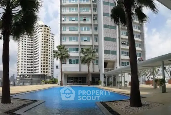 Luxurious high-rise building with stunning pool and palm trees, perfect for urban living.
