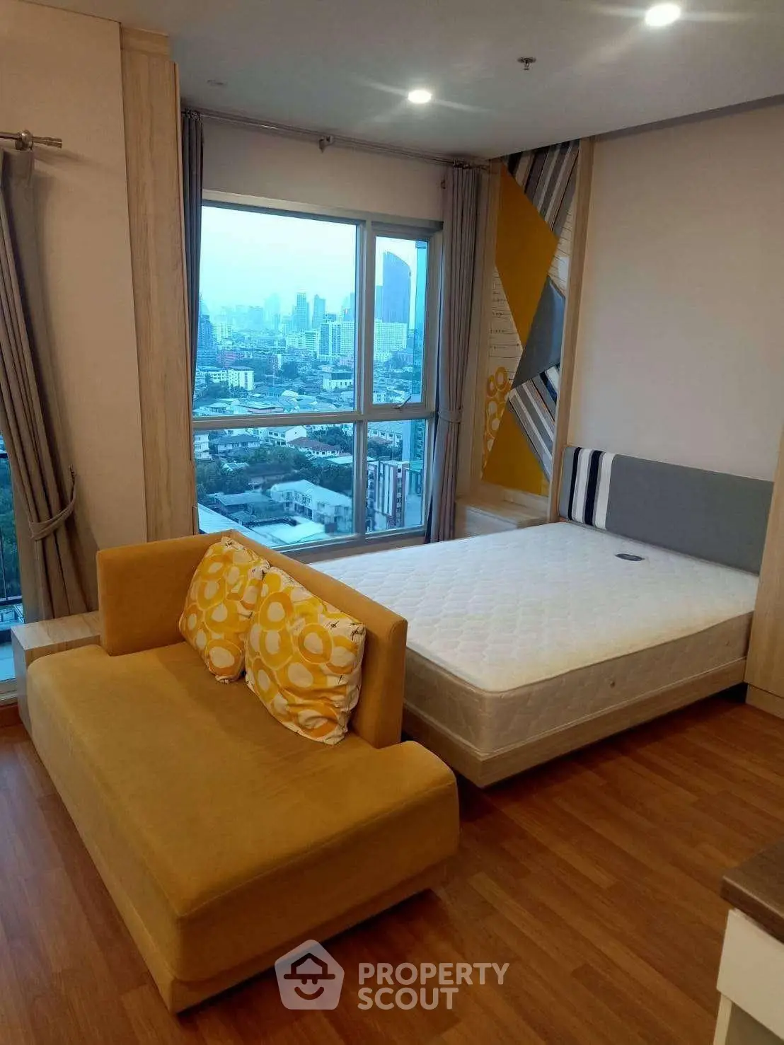 Modern bedroom with city view, featuring cozy sofa and stylish decor.