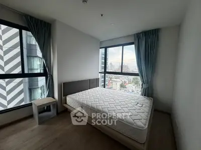 Modern bedroom with large windows offering stunning city views, featuring a comfortable bed and stylish decor.