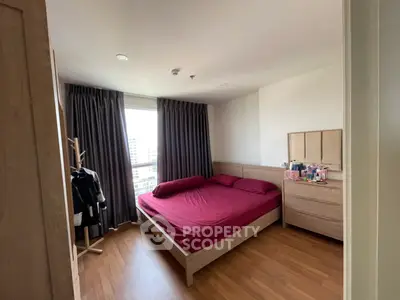Spacious bedroom with wooden flooring and large window offering city views