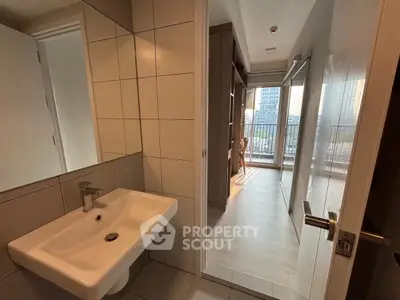Modern apartment with sleek bathroom and bright hallway leading to a balcony with city view.