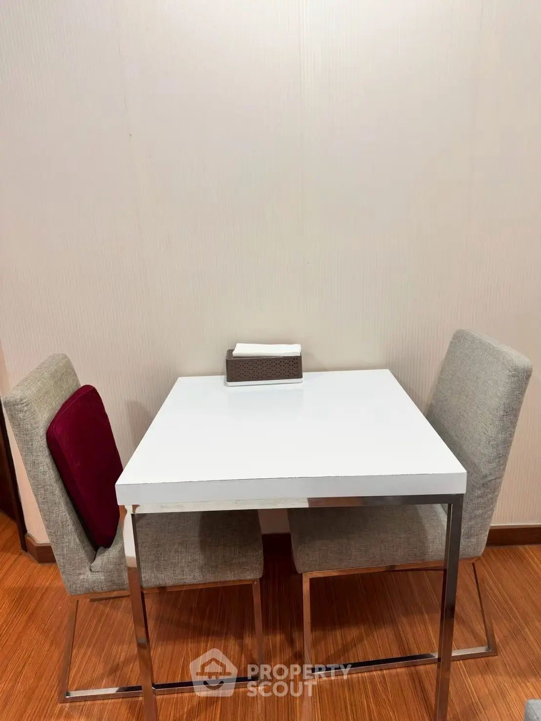 Modern dining area with sleek white table and stylish chairs on wooden flooring.