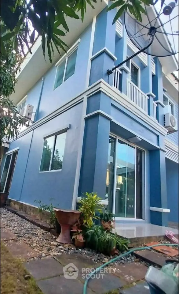Modern blue two-story house with lush garden and large windows