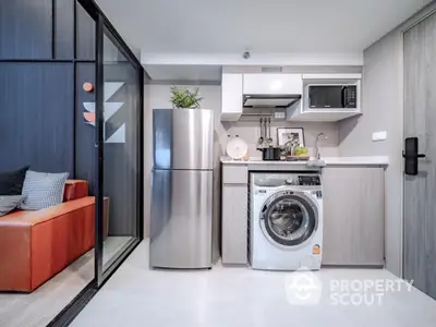 Modern compact kitchen with stainless steel fridge and washing machine