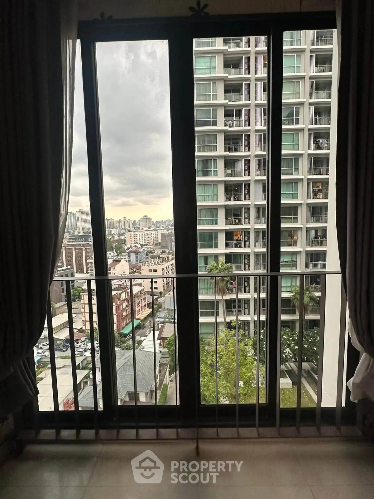 Stunning cityscape view from a modern apartment balcony with floor-to-ceiling windows.