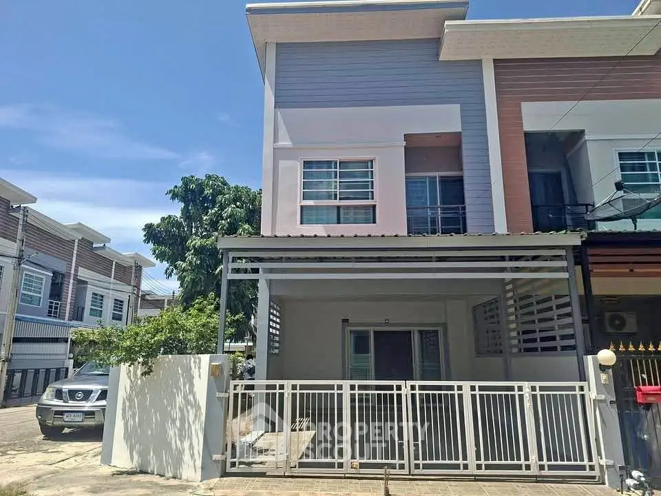 Modern townhouse exterior with gated entrance and driveway in a sunny neighborhood.
