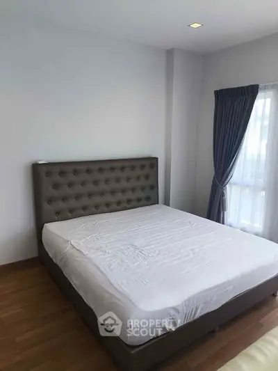 Spacious bedroom with elegant bed and natural light from large window.