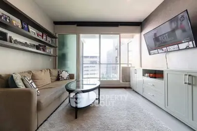 Modern living room with cozy sofa, wall-mounted TV, and large window offering natural light.