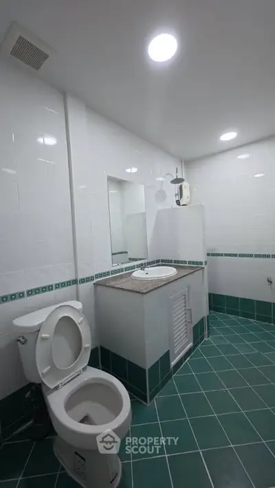 Modern bathroom with green tiled floor and white fixtures
