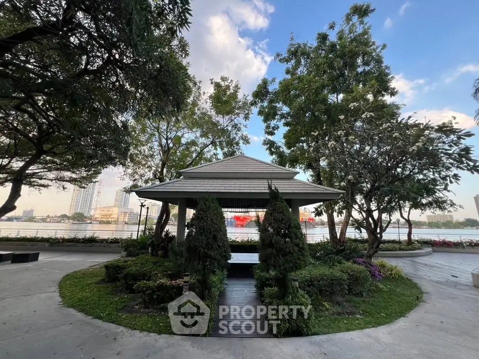 Serene riverside garden with lush greenery and a charming gazebo, perfect for relaxation and outdoor enjoyment.