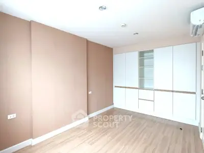 Spacious empty room with built-in storage and wooden flooring