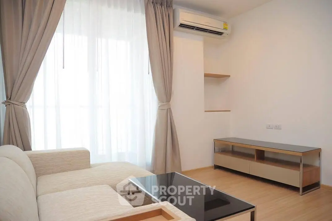 Modern living room with natural light, featuring a cozy sofa and sleek air conditioning unit.