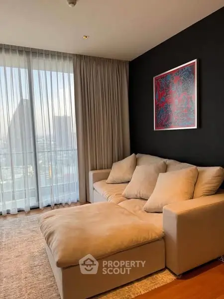 Modern living room with cozy beige sofa and city view through large window.
