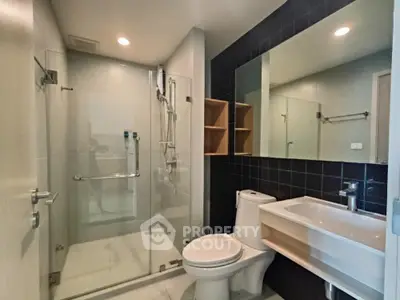 Modern bathroom with glass shower and sleek fixtures in contemporary apartment.