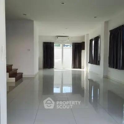 Spacious empty living room with glossy tiled floors and large windows.