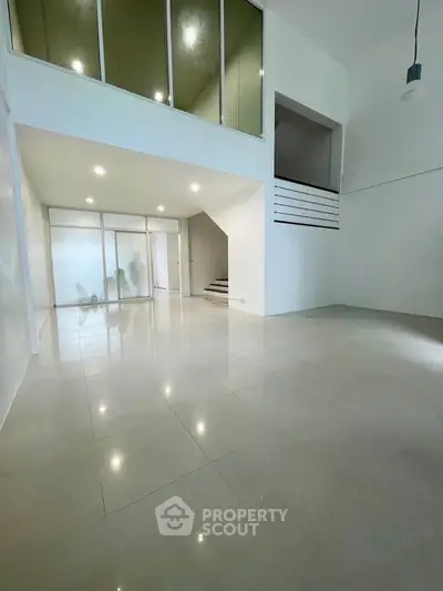 Spacious modern living room with high ceilings and sleek tile flooring, perfect for contemporary living.