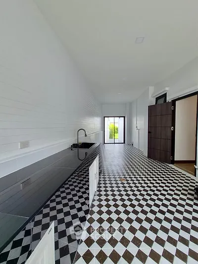 Sleek modern kitchen with black and white checkered floor and glossy countertops, leading to a bright window view.