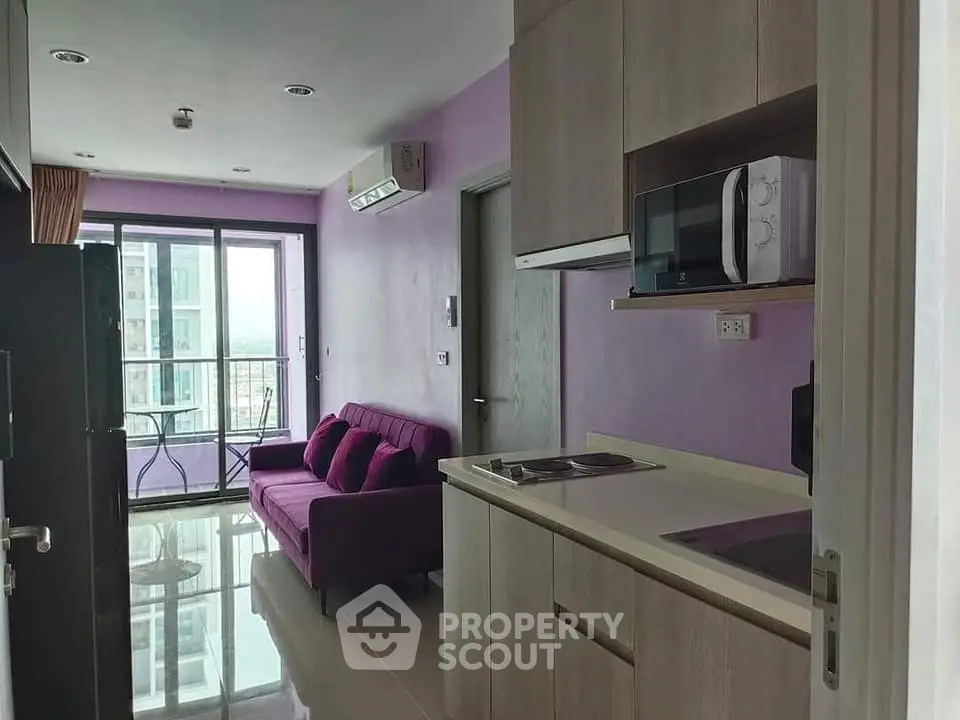Modern apartment with compact kitchen and cozy living area featuring a balcony view.