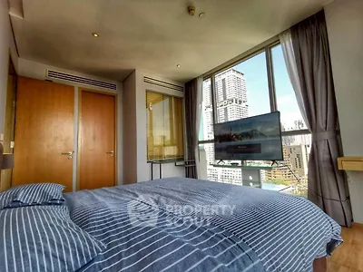 Modern bedroom with city view, featuring large windows and stylish decor in a high-rise apartment.