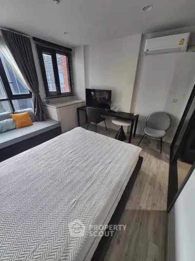 Modern bedroom with stylish decor, featuring a cozy bed, desk, and large window for natural light.