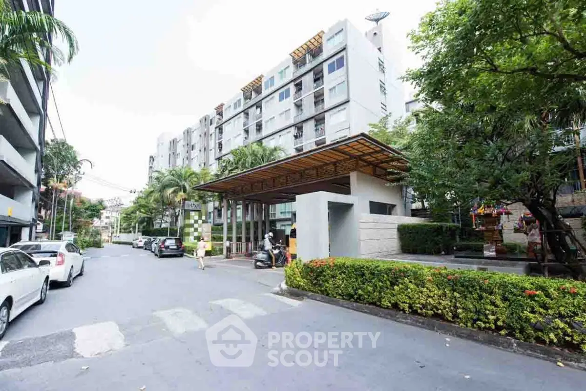 Modern apartment building with lush greenery and street view, showcasing urban living.