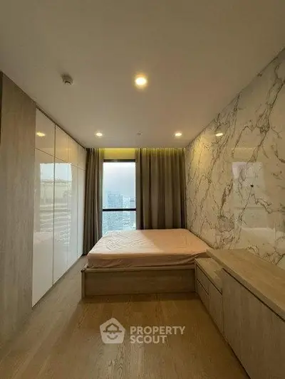 Modern bedroom with marble accent wall and city view window, featuring sleek wooden furniture.
