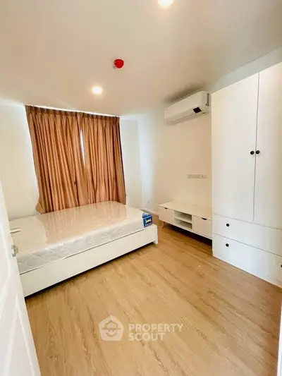 Modern bedroom with wooden flooring, air conditioning, and ample storage space.