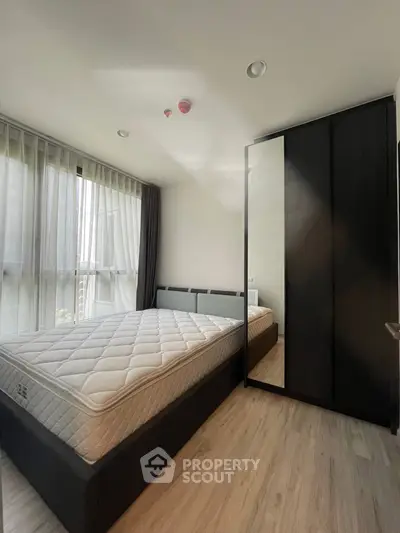 Modern bedroom with large window, sleek wardrobe, and comfortable bed in stylish apartment.