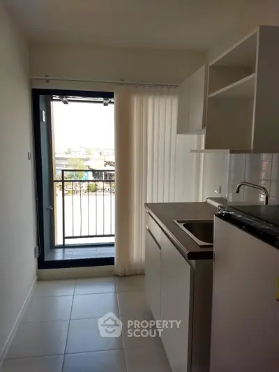 Modern kitchen with balcony view, sleek cabinets, and natural light